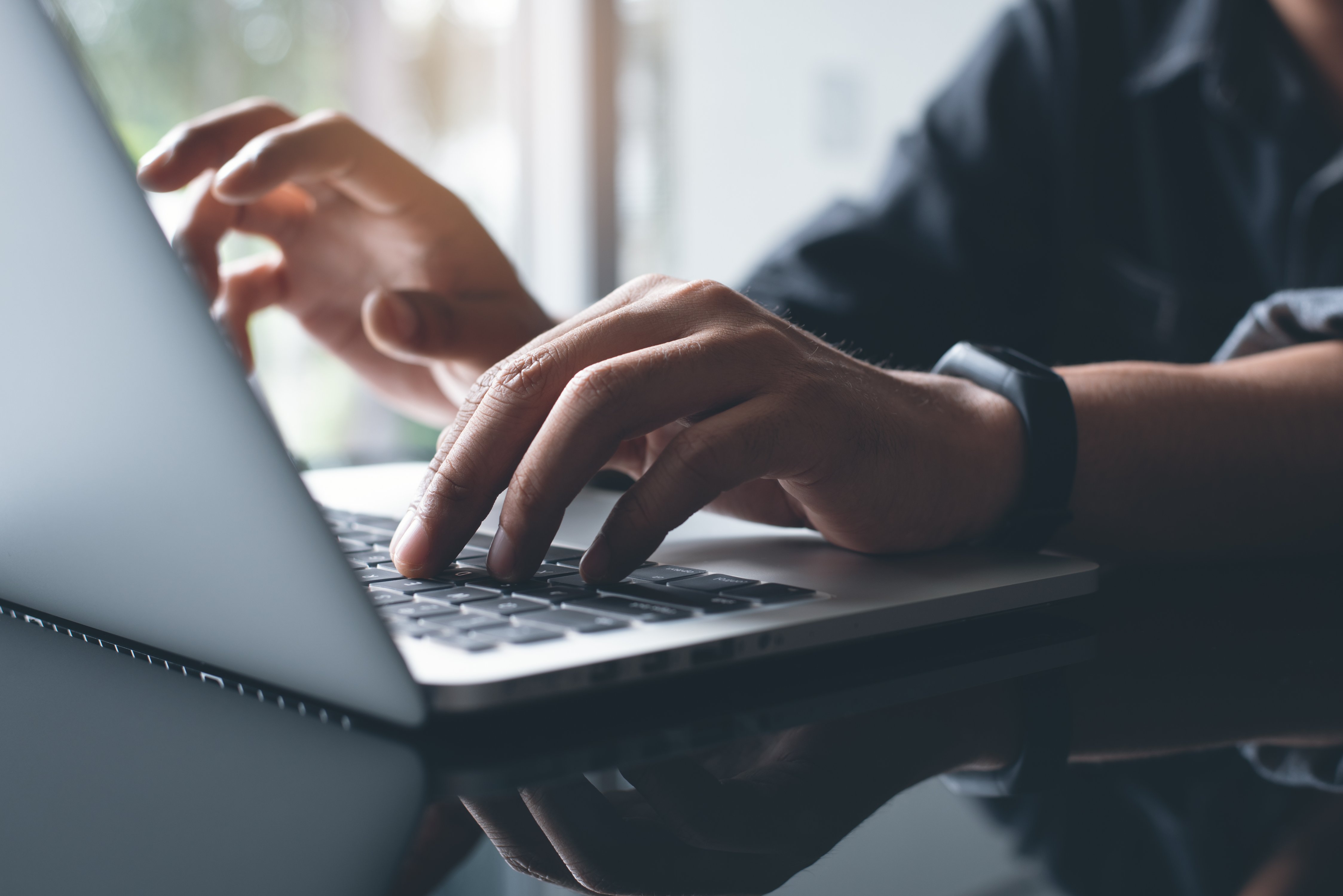 man typing on laptop keyboard